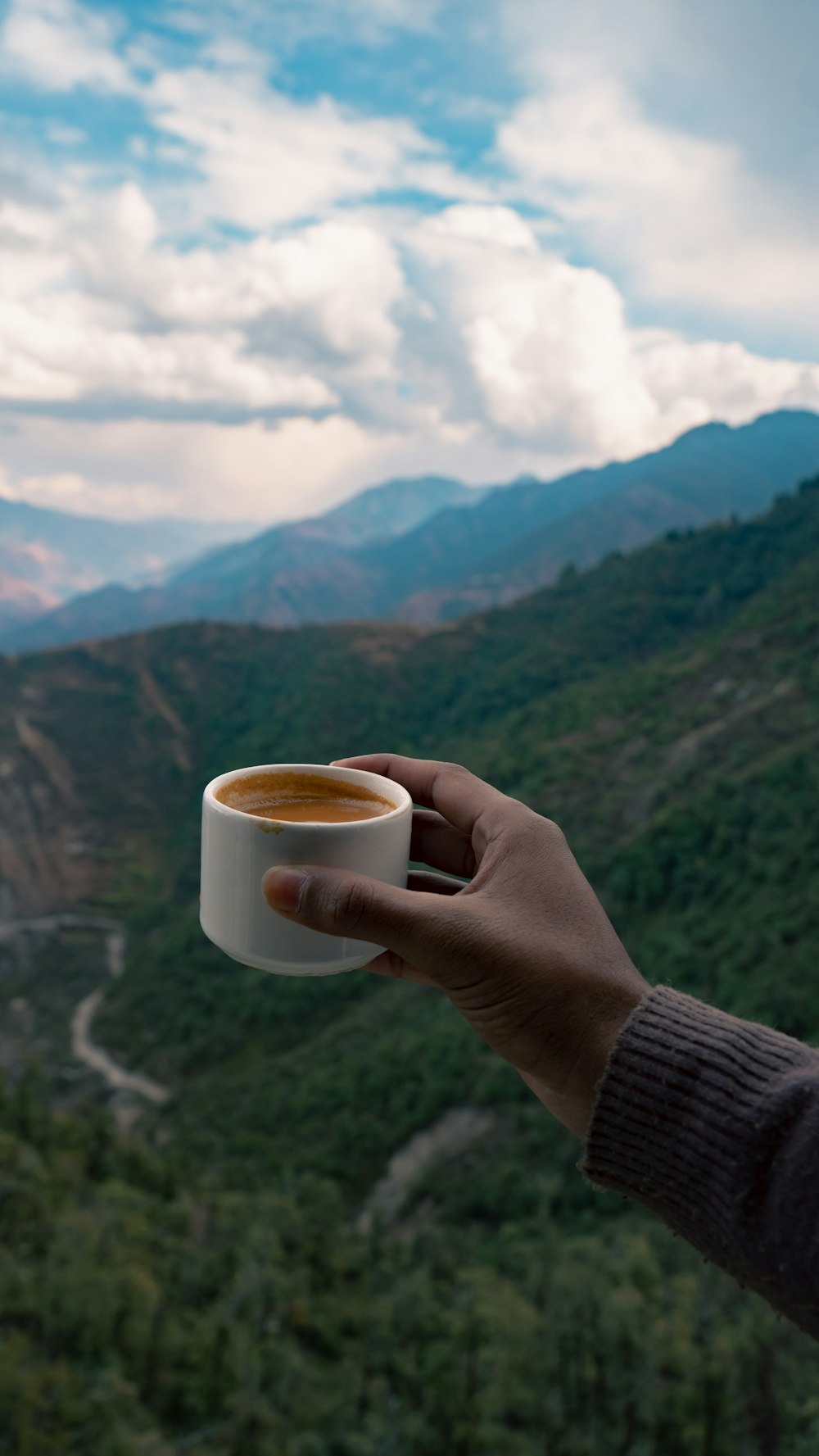 a person holding a cup of coffee in their hand