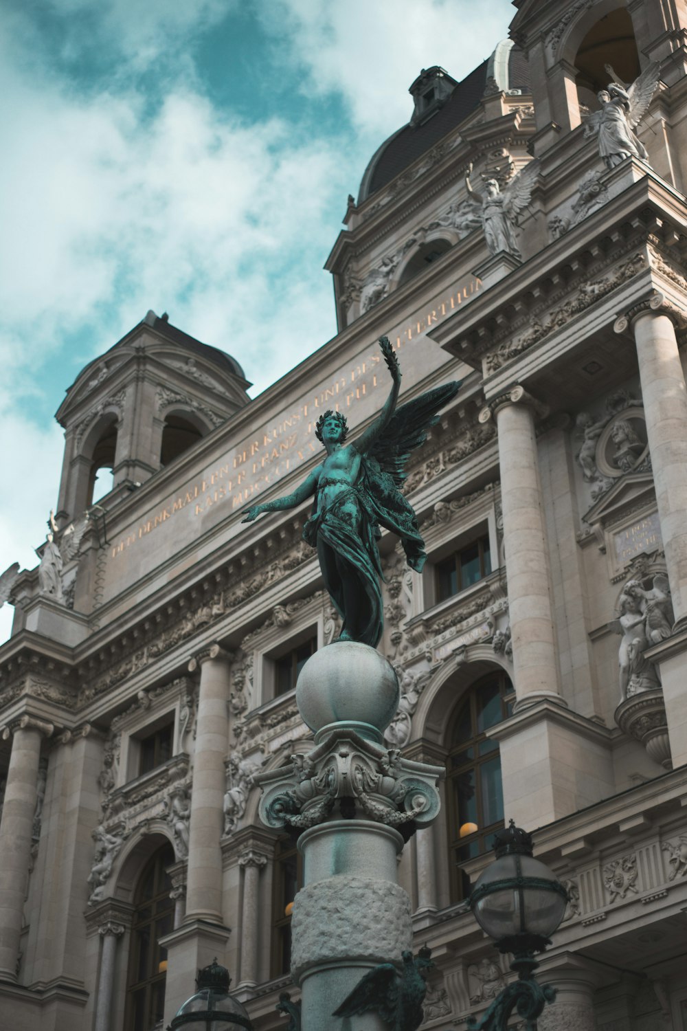 a statue on top of a light pole in front of a building