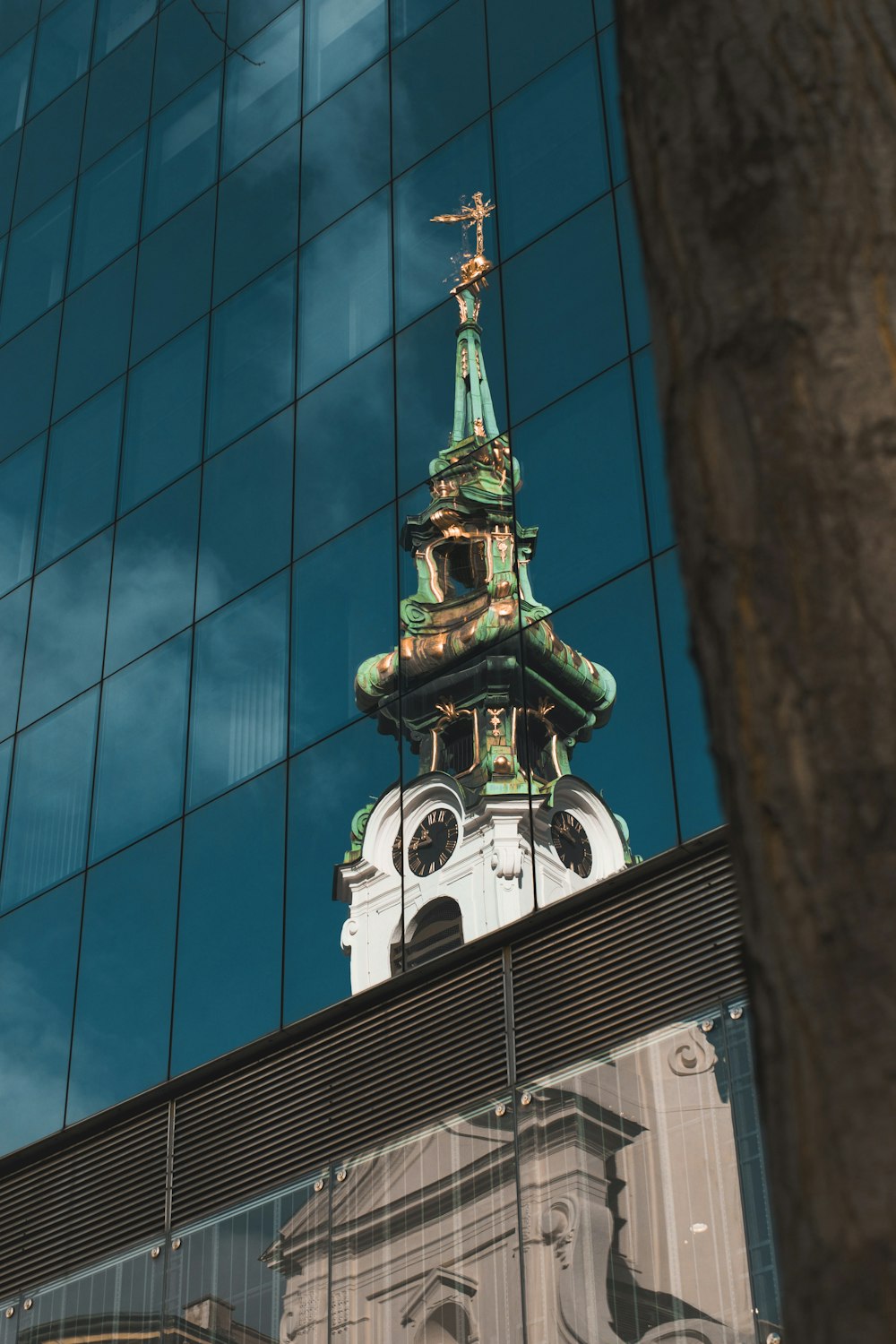 a clock tower is reflected in the windows of a building
