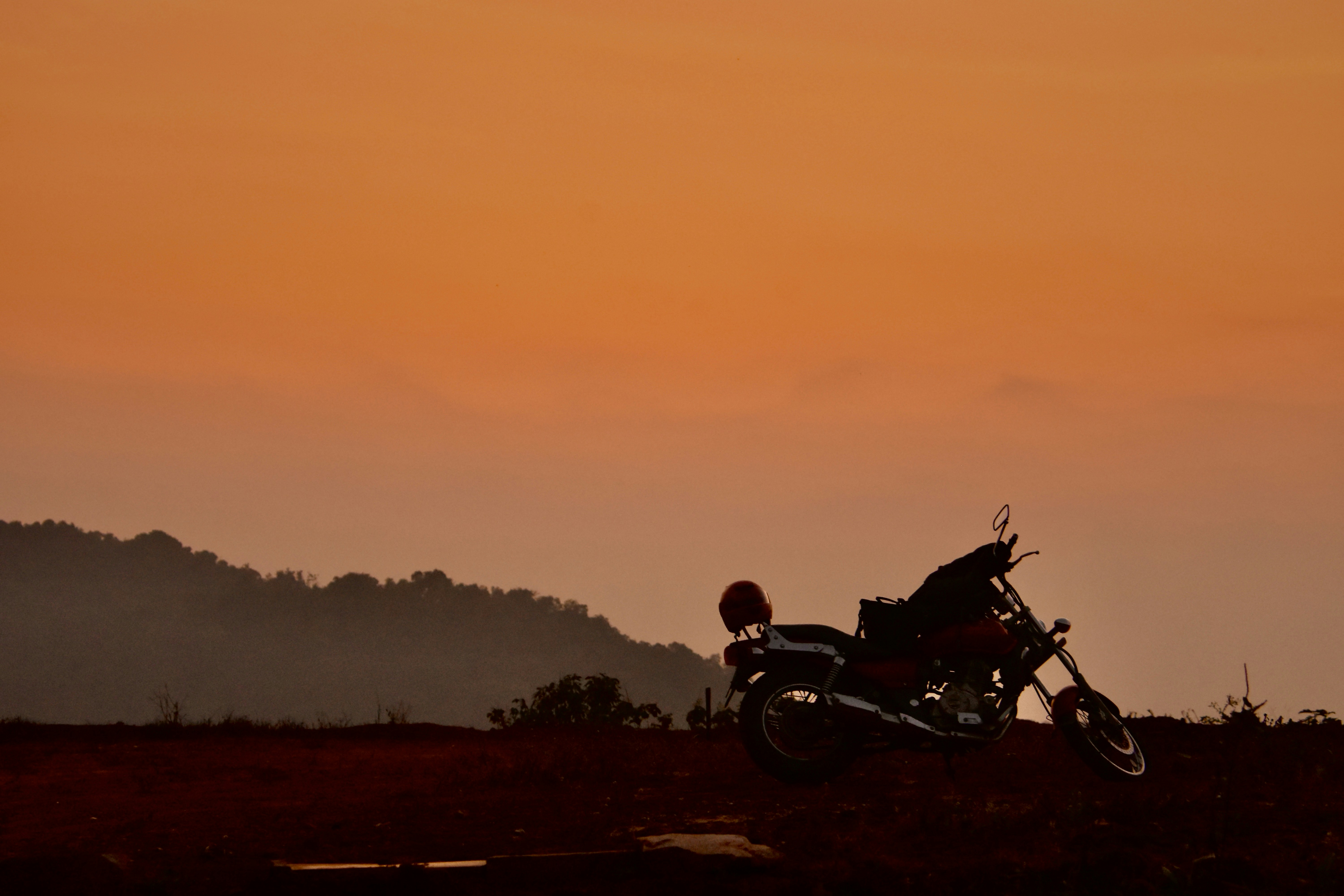 Una motocicleta estacionada en la cima de una colina al atardecer