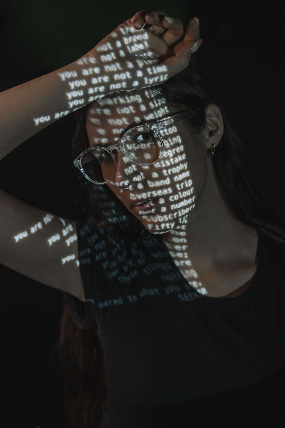 a woman wearing glasses and a t - shirt with words projected on it