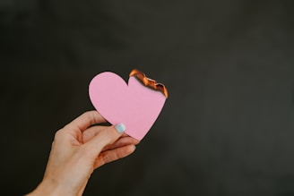 a person holding a pink heart shaped piece of paper