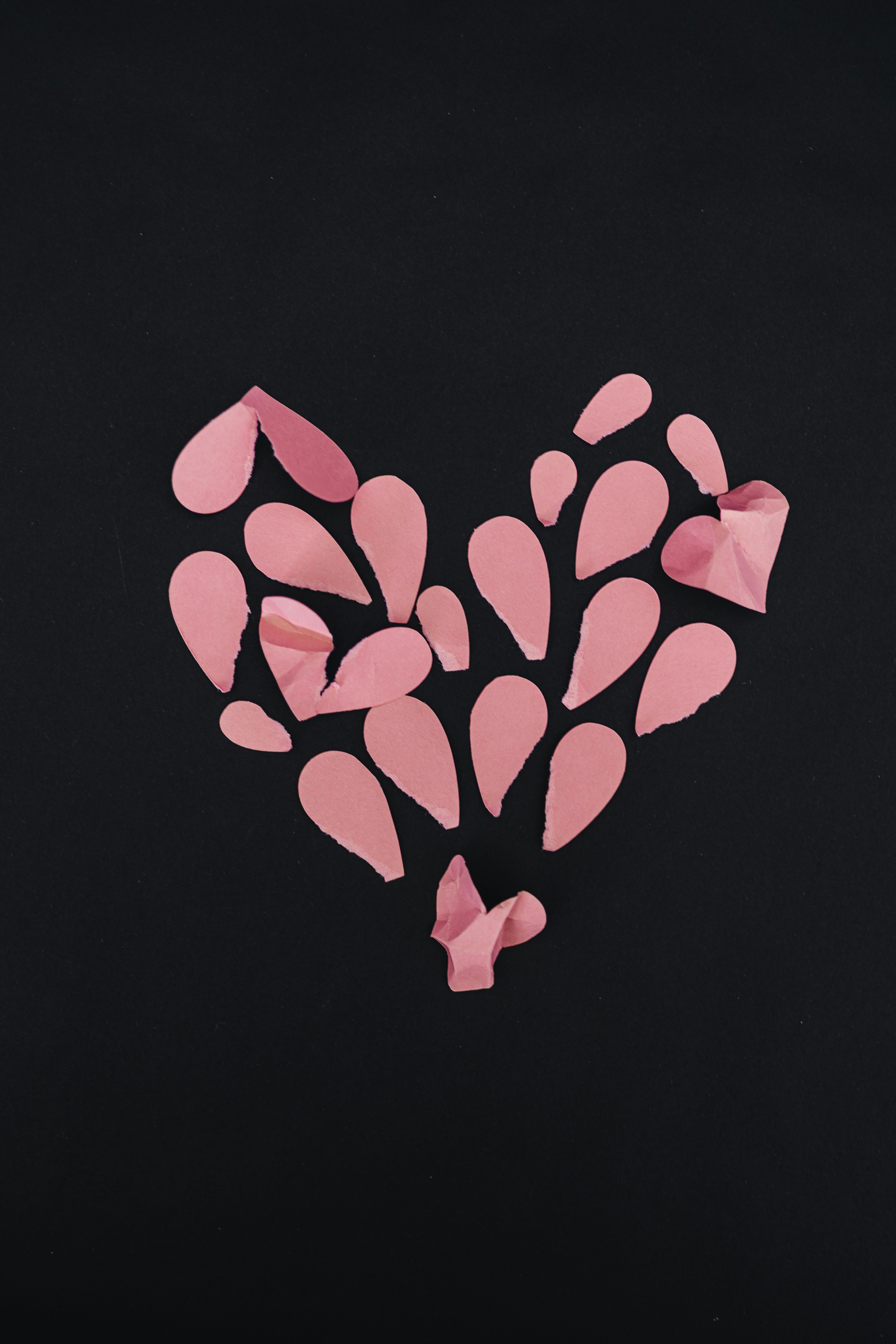 a heart made out of pink paper on a black background