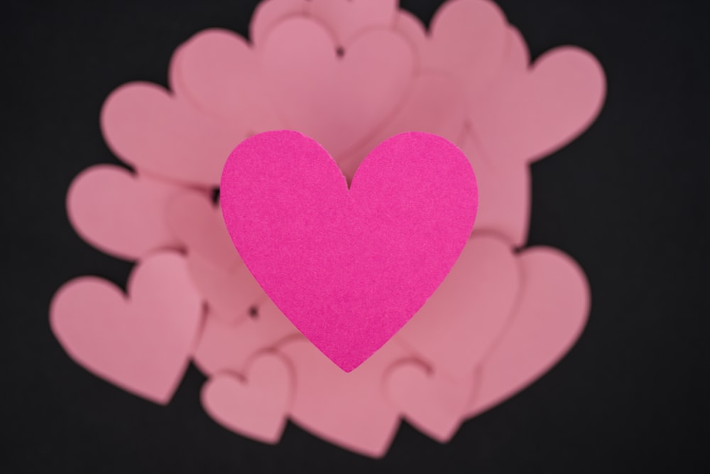 Un cuore rosa circondato da cuori rosa su sfondo nero