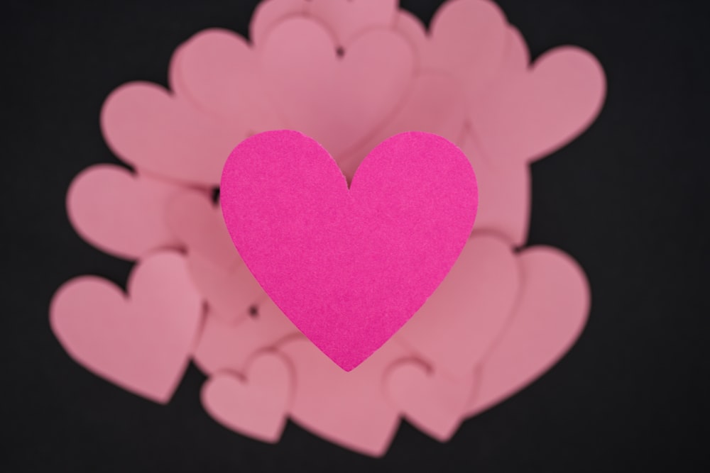 a pink heart surrounded by pink hearts on a black background