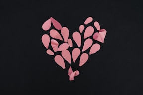 a heart made out of pink paper on a black background