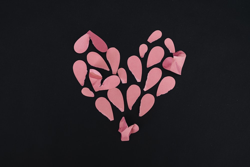 a heart made out of pink paper on a black background