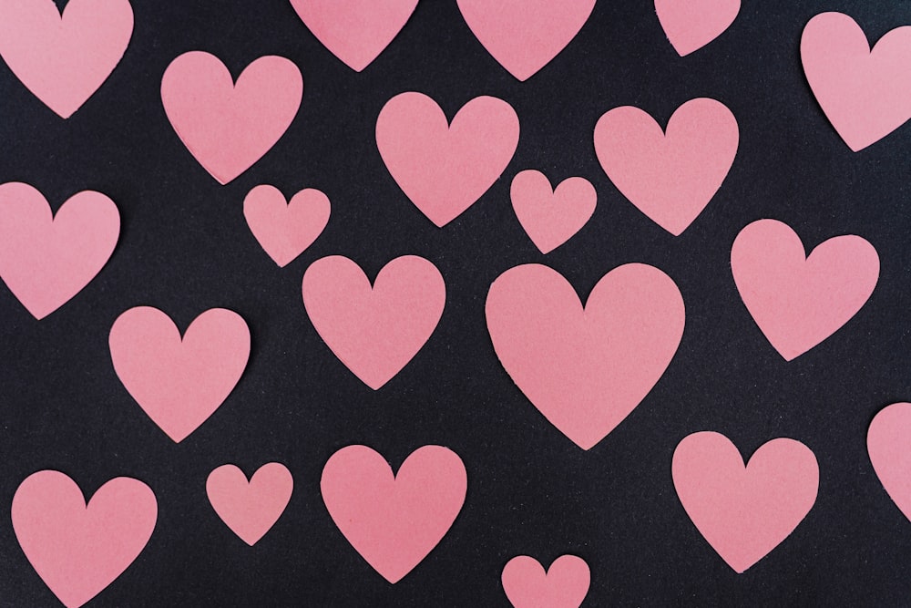 a bunch of pink hearts on a black background