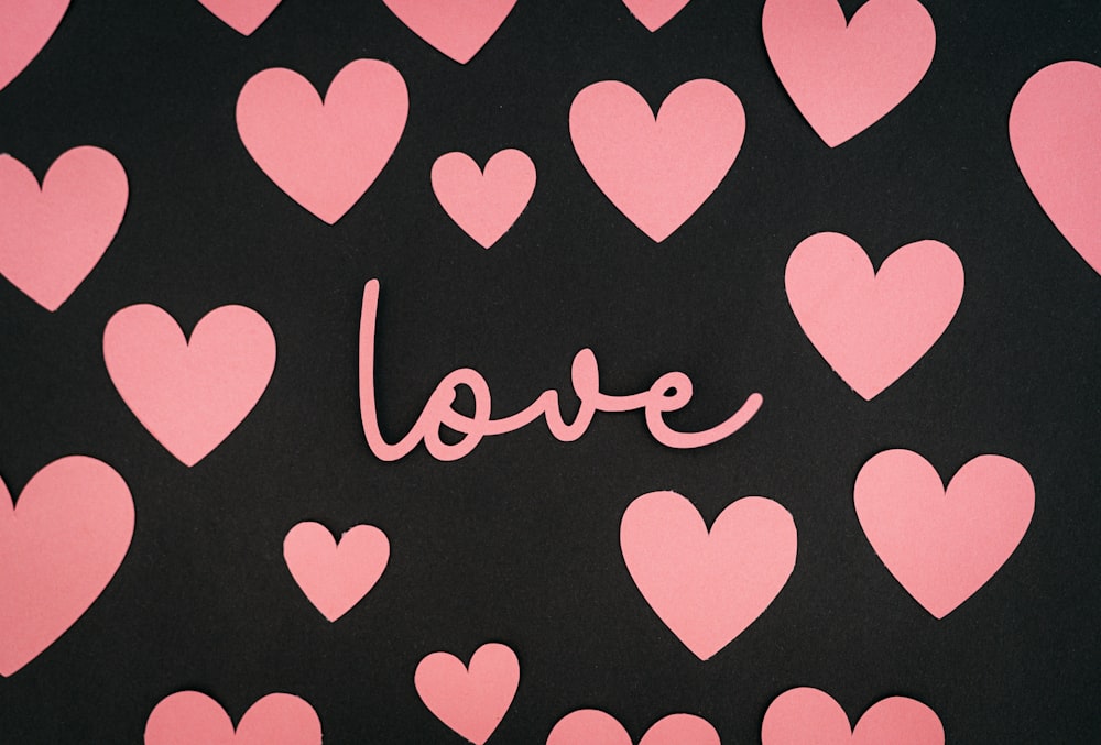 a black background with pink hearts and the word love