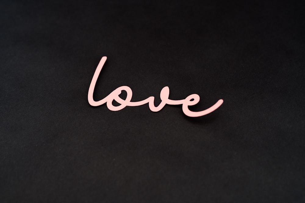 the word love written in pink on a black background