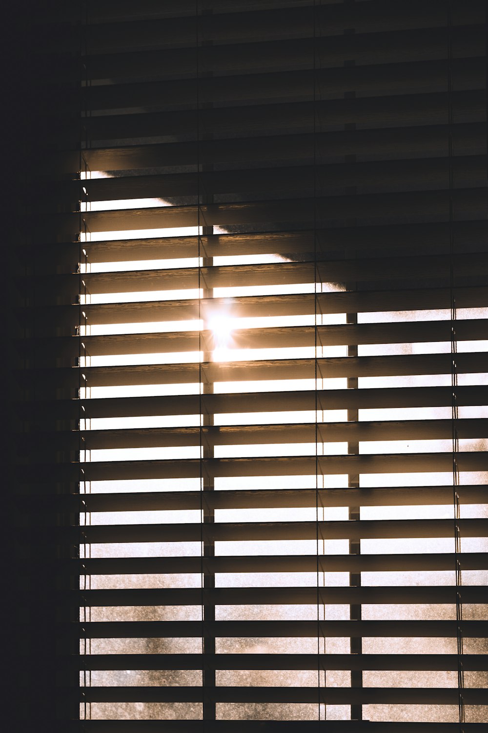 the sun is shining through the blinds of a window