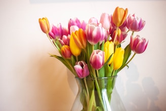 A vibrant birthday bouquet featuring colorful tulips and daisies in a bright vase.