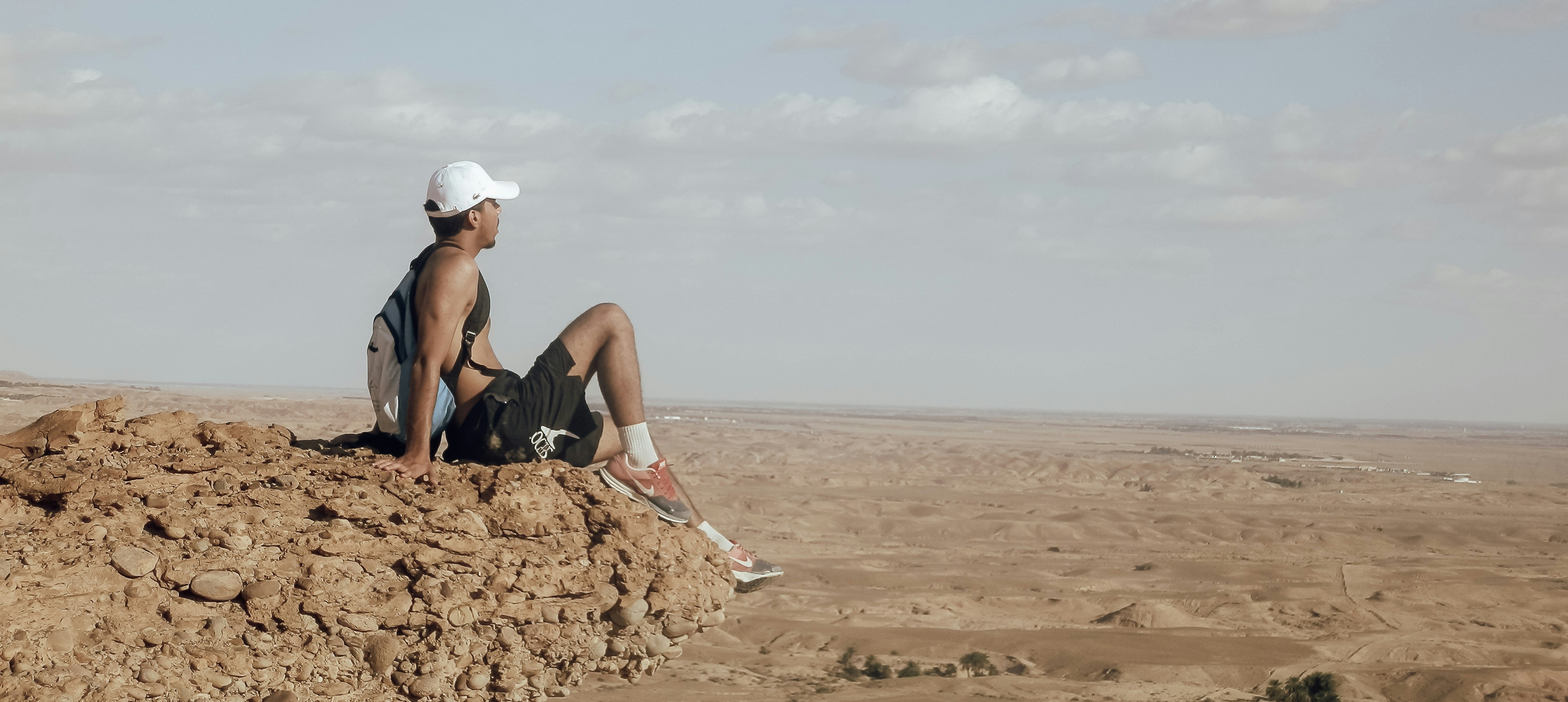 a man sitting on top of a rock in the desert