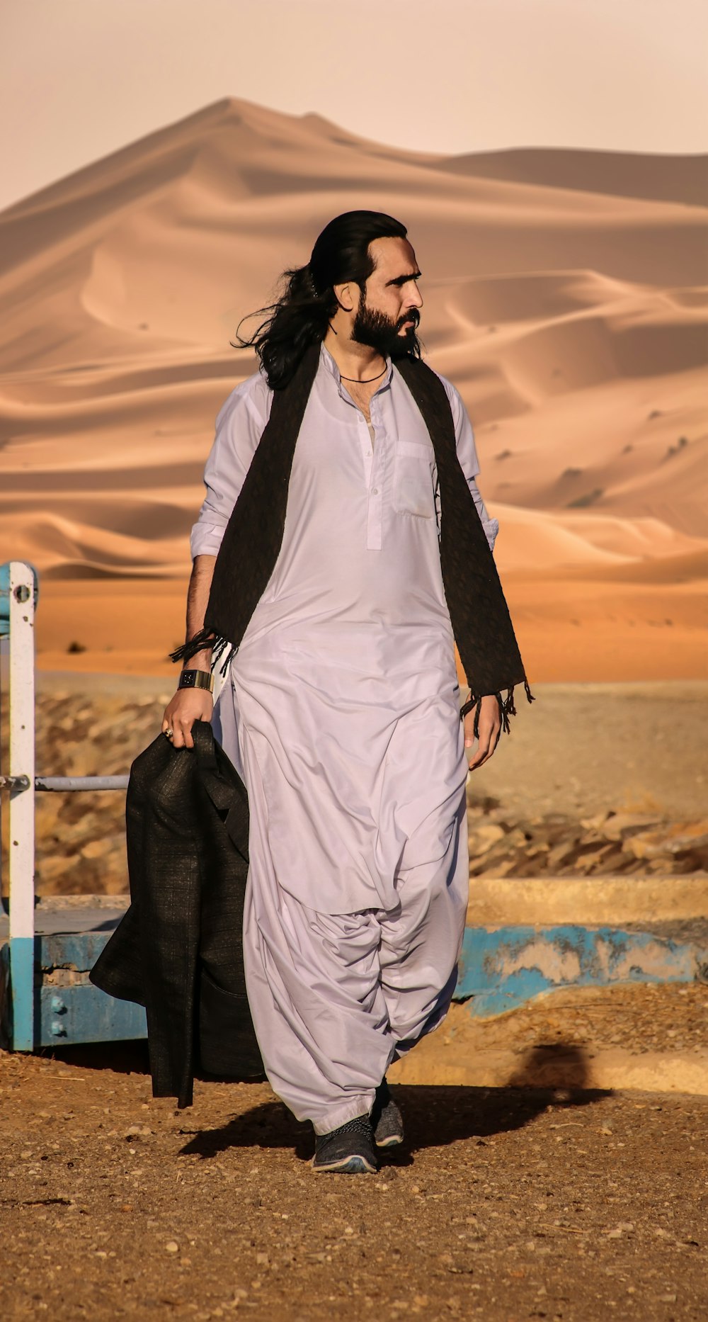 a man with long hair and a beard walking in the desert