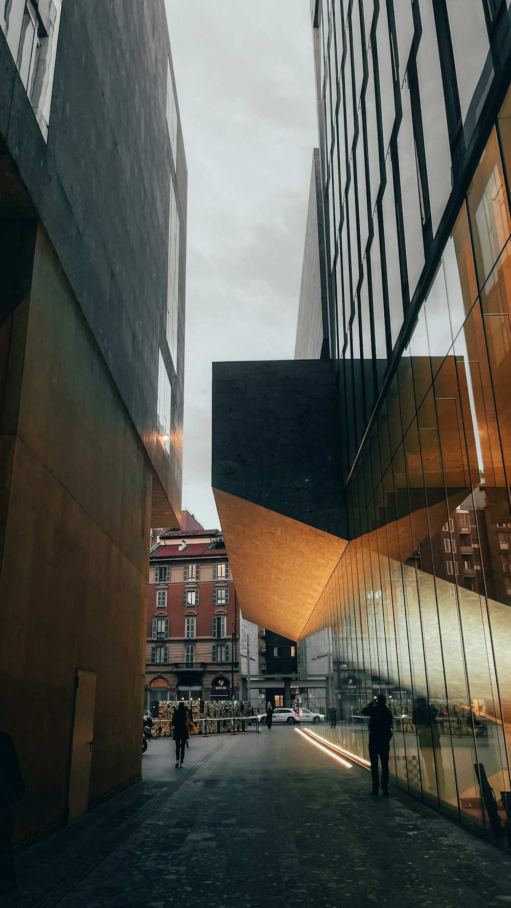 a couple of people walking down a street next to tall buildings