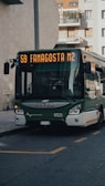 a green and white bus driving down a street
