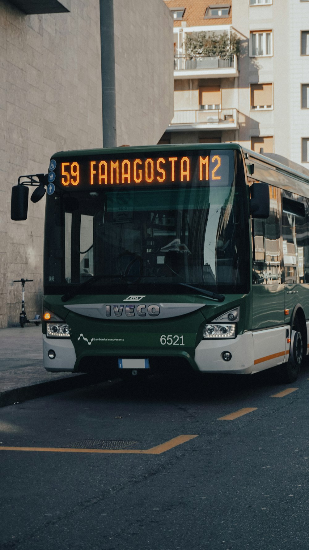 a green and white bus driving down a street