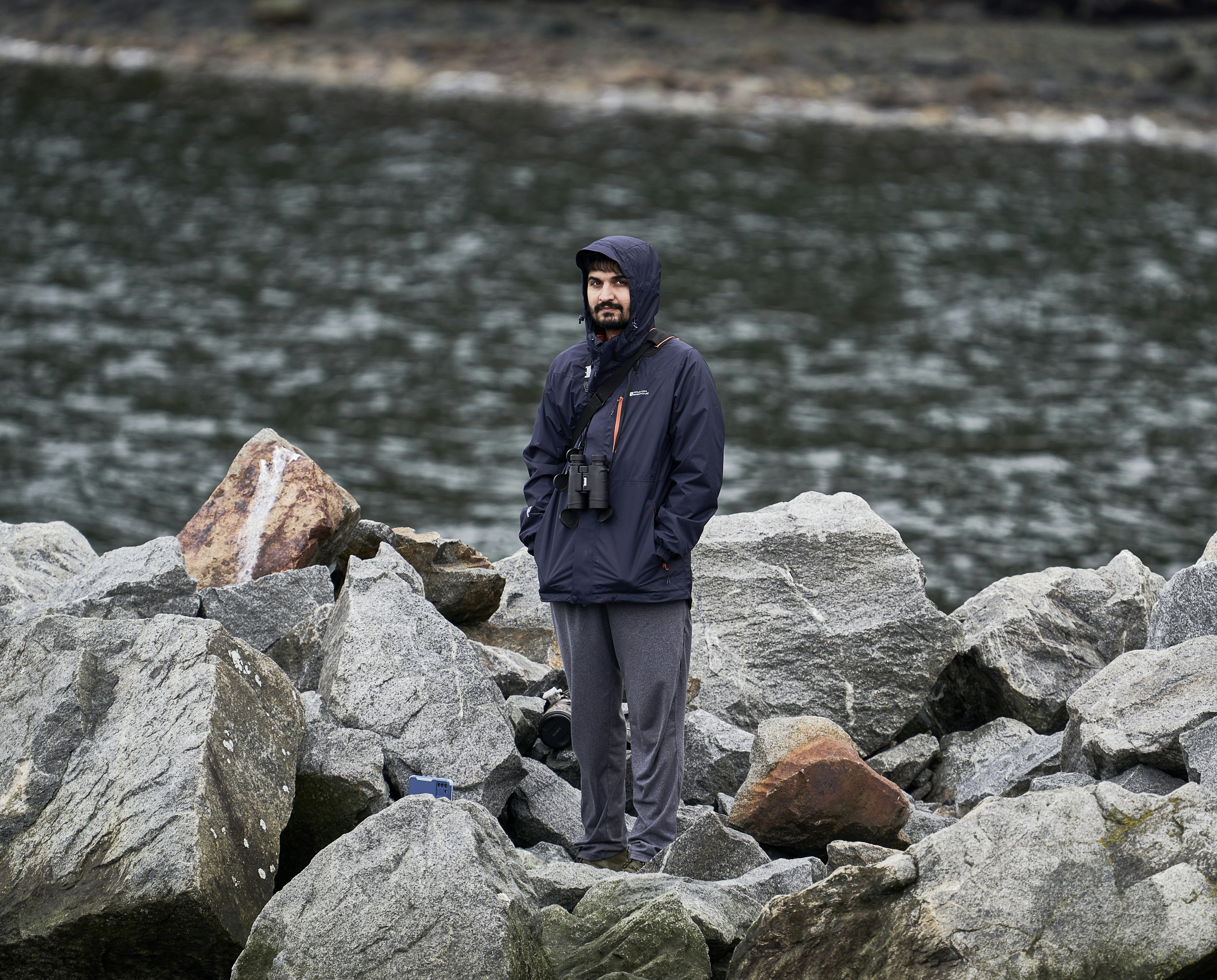 a man standing on rocks near a body of water