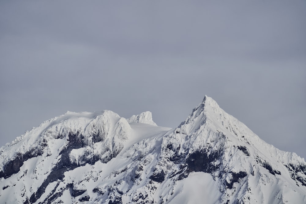 a large mountain covered in snow under a cloudy sky