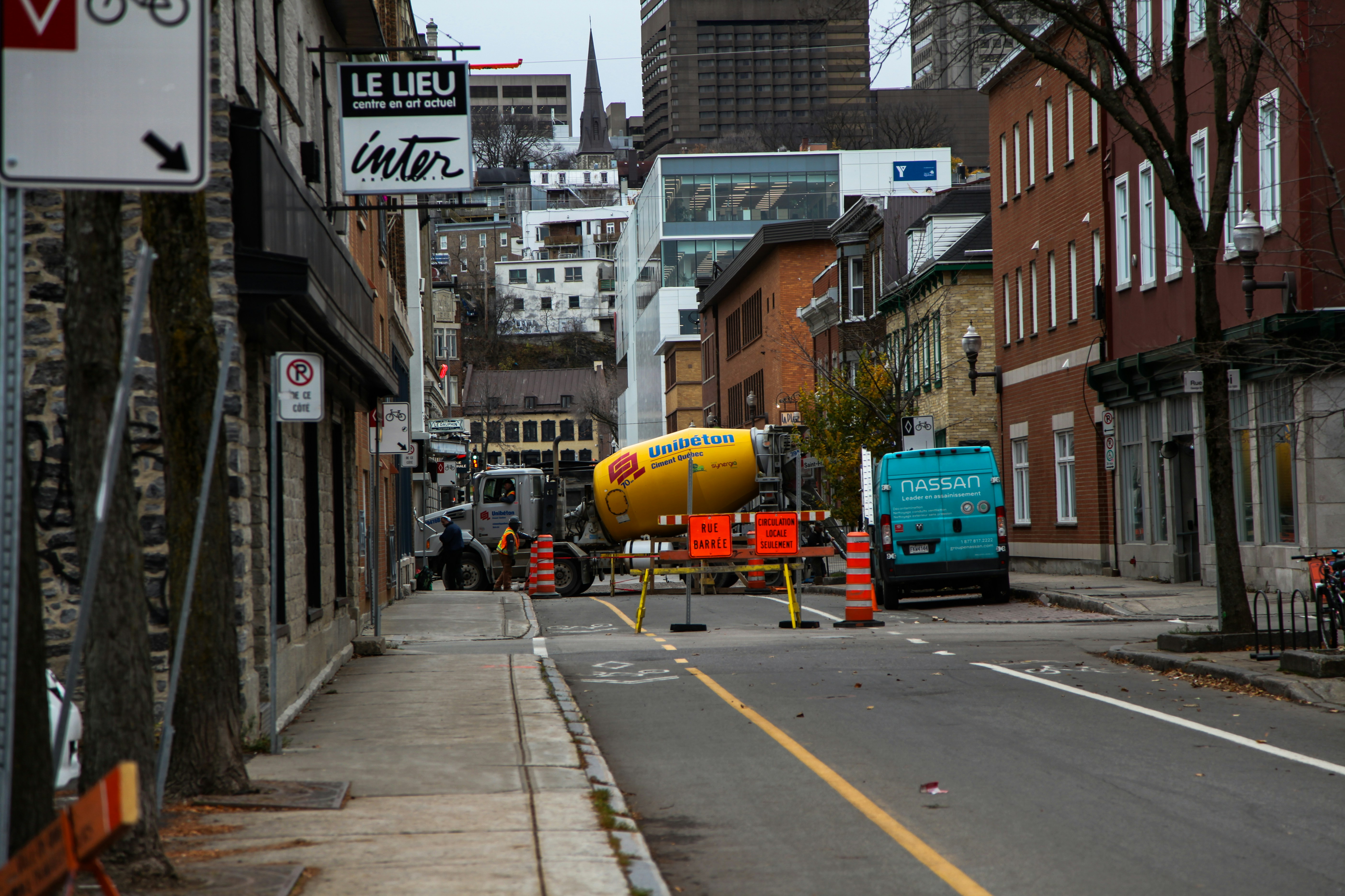 a yellow and red cement mixer sitting on the side of a road