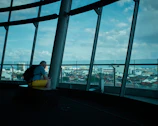 A tourist using a Voltiva power bank while sitting on a city bench with landmarks in the background.
