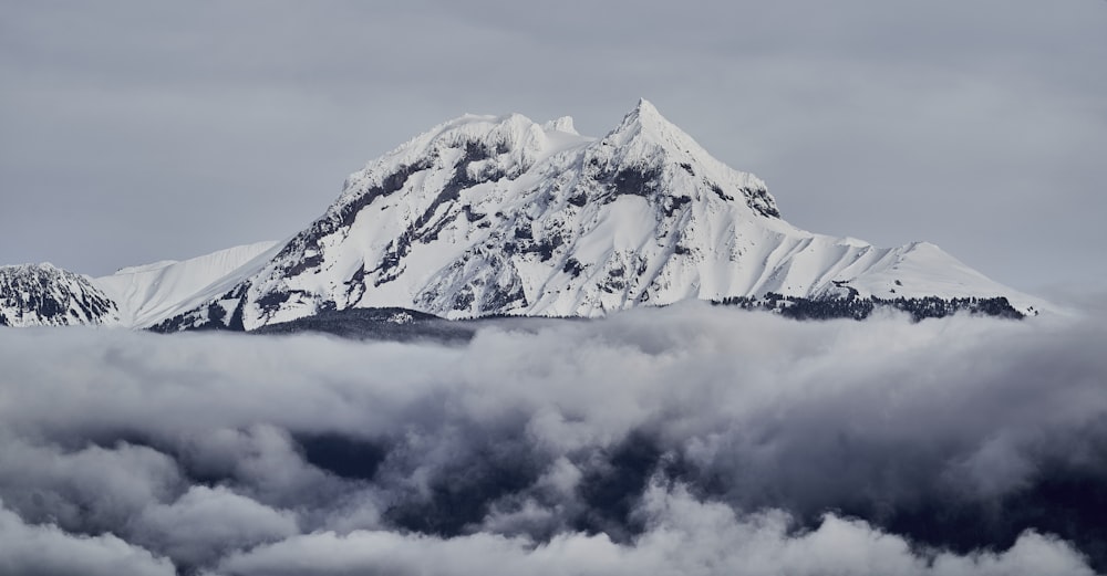 a mountain covered in snow surrounded by clouds