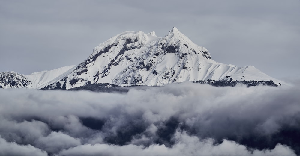 uma montanha coberta de neve cercada por nuvens