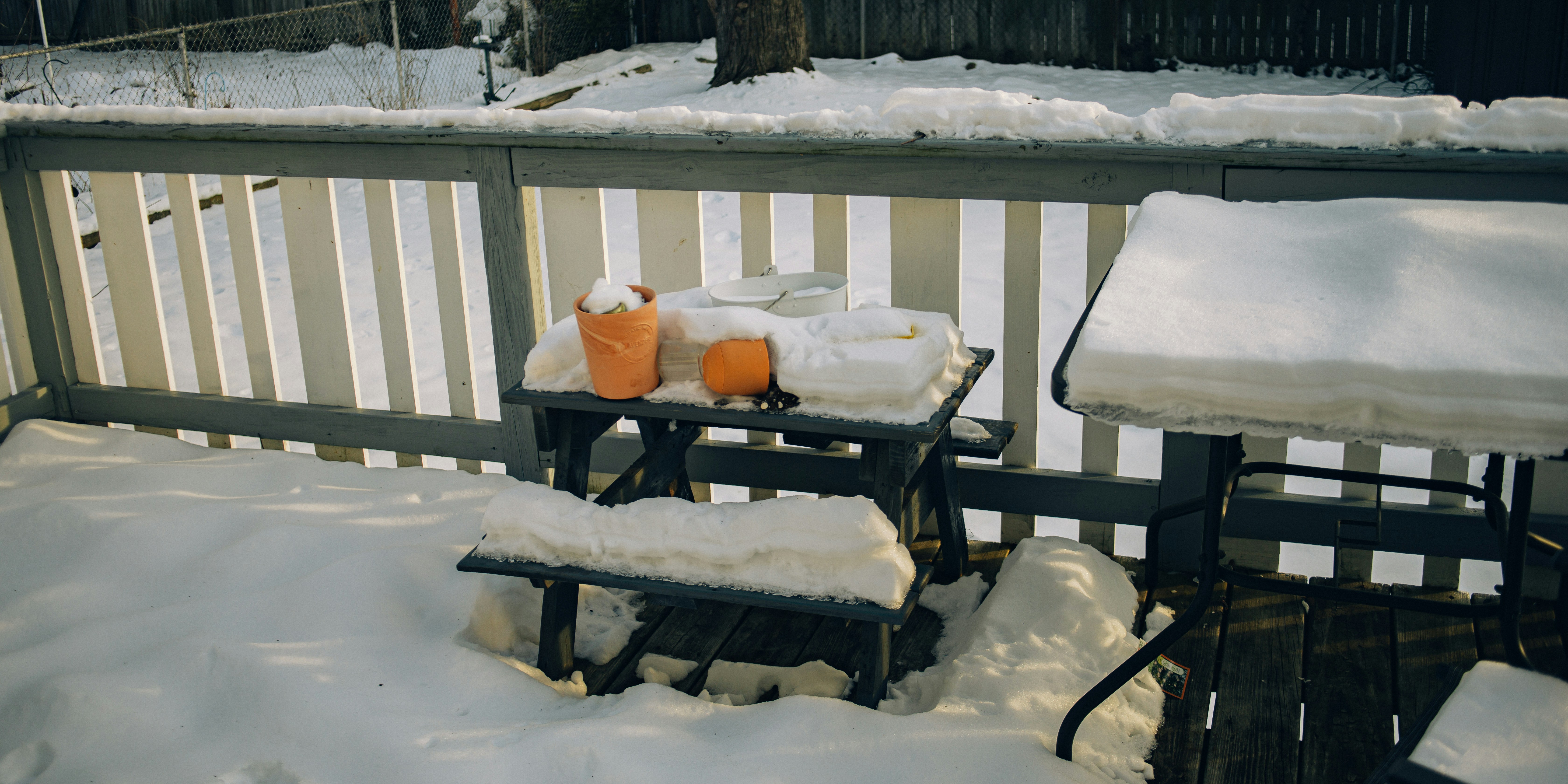 a couple of benches covered in snow next to a fence