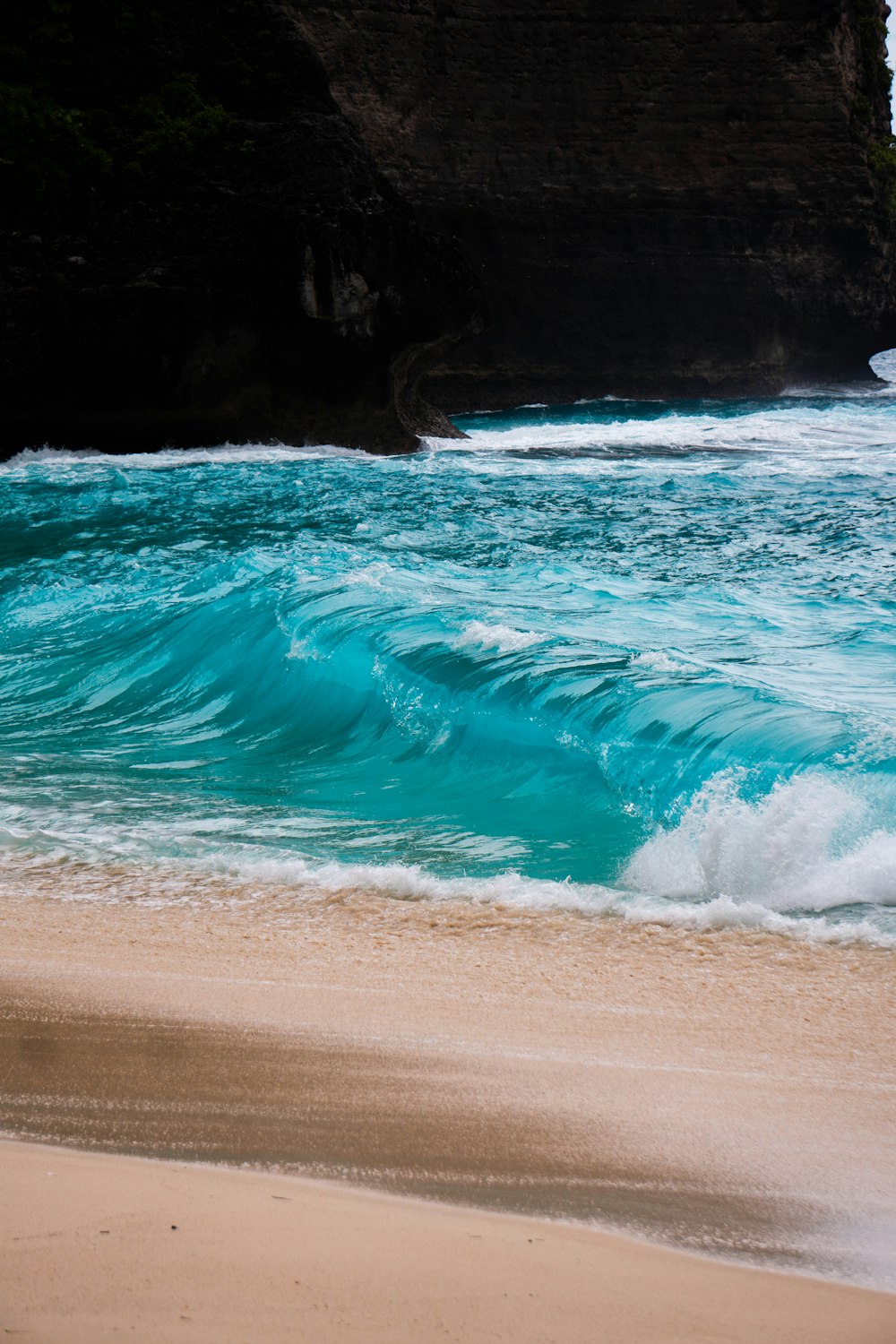 a sandy beach with a wave coming in to shore