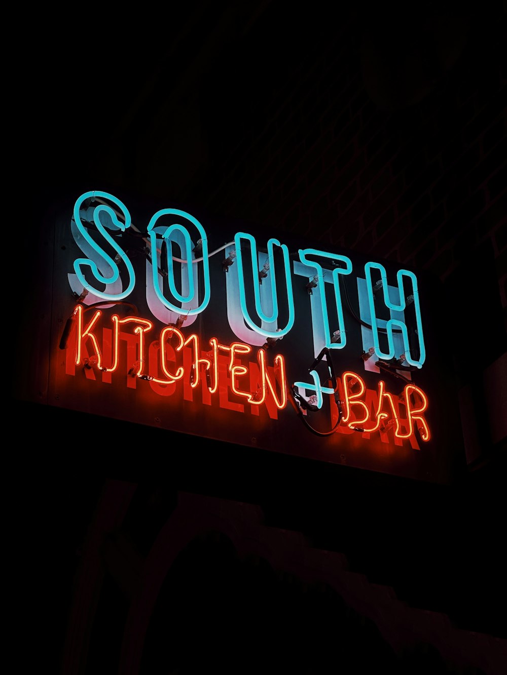 a neon sign that says south kitchen and bar