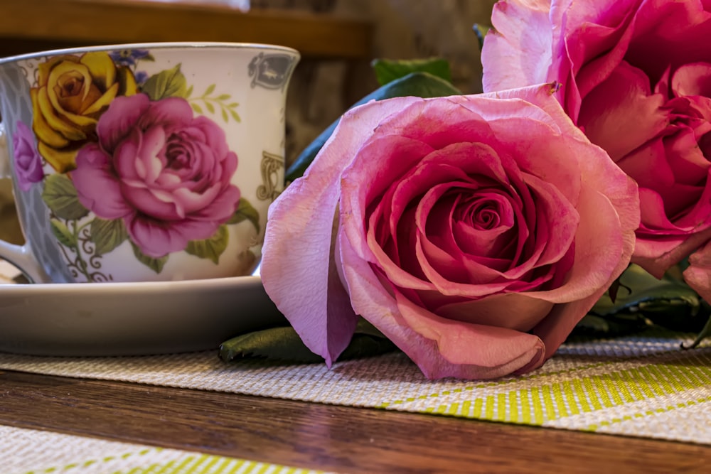 a couple of pink roses sitting on top of a table