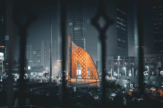 a view of a building through a fence at night