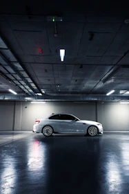 Sleek sports car parked in a minimalist garage illuminated by soft industrial lighting.
