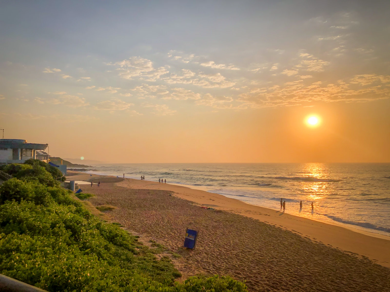 The sun is setting over the beach and the ocean