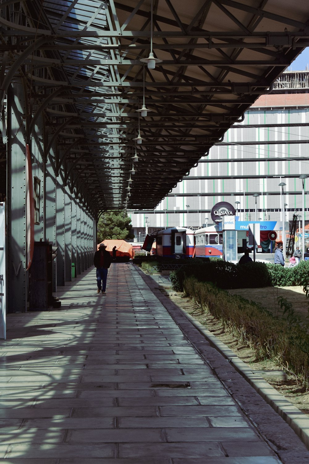 a person walking down a walkway under a building