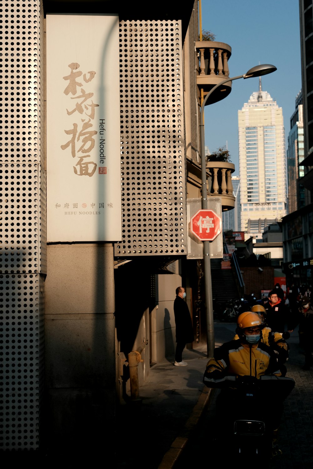 a man riding a motorcycle down a street next to tall buildings