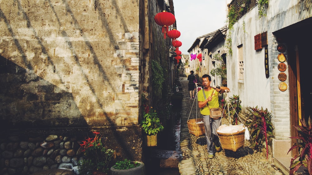 a man carrying a basket down a narrow street