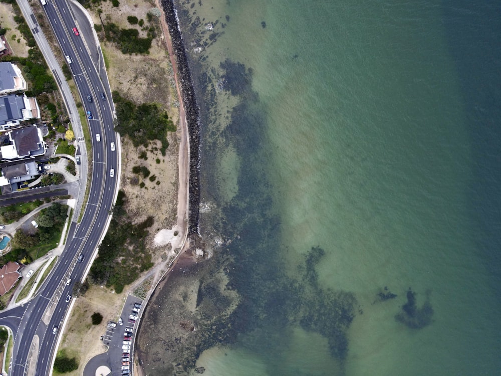 an aerial view of a road next to a body of water