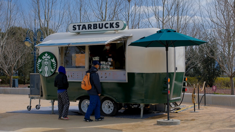 a couple of people standing outside of a starbucks truck