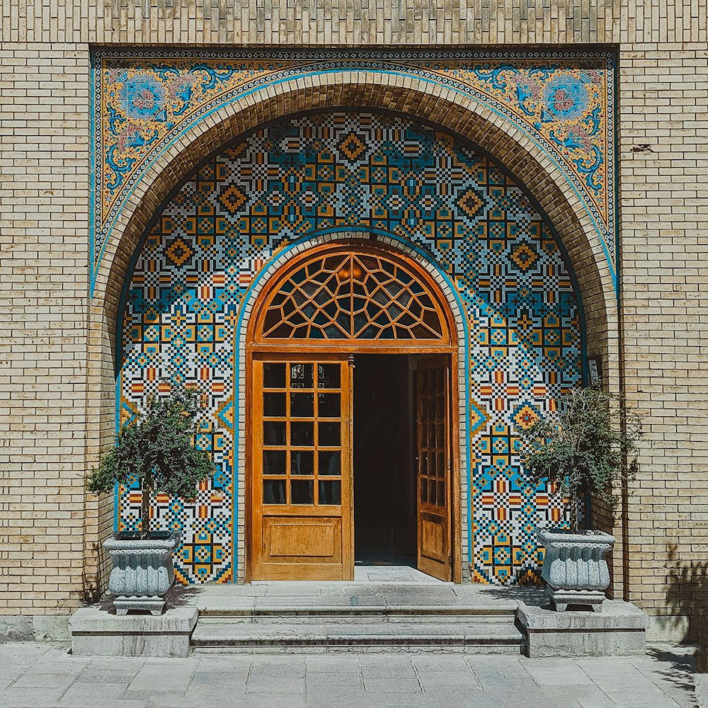 a building with a large wooden door and two planters in front of it