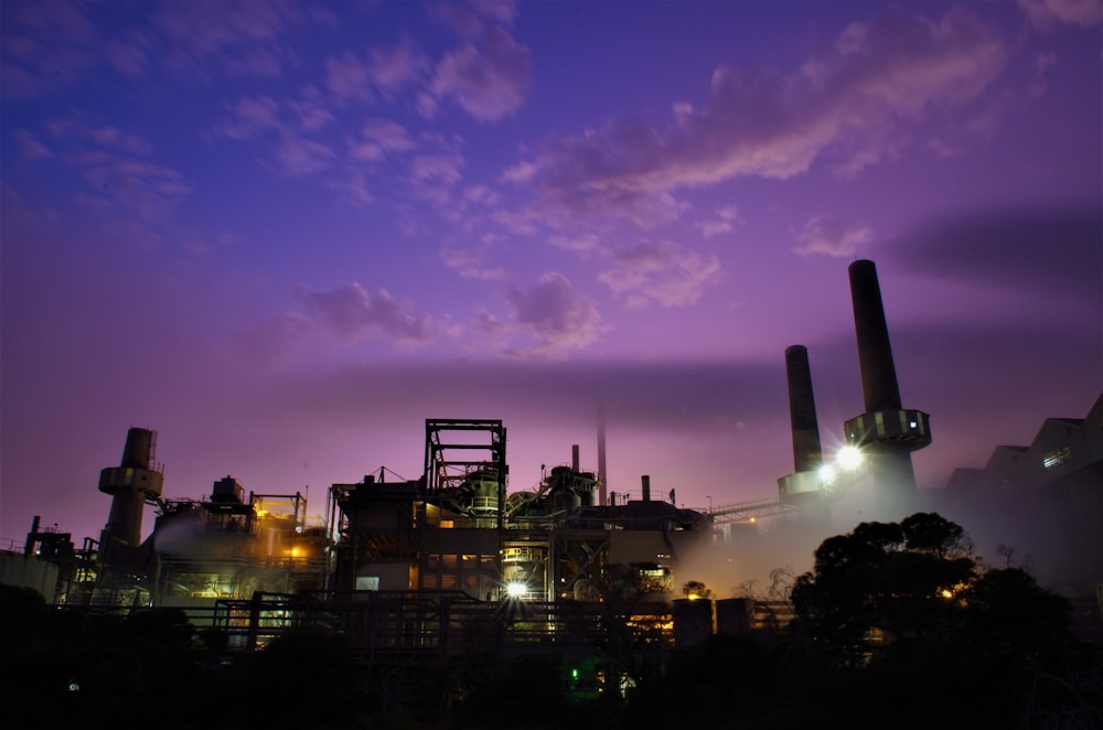 a factory with smokestacks and lights at night