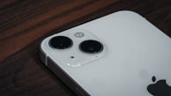 A close-up of an iPhone displayed on a wooden table.