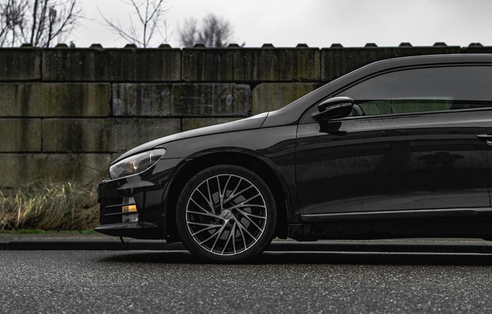 a black car parked in front of a brick wall