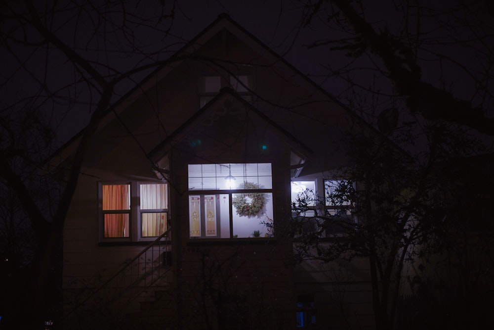 a house is lit up at night with a wreath on the window