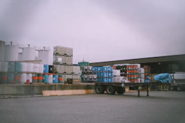 A detailed shot of raw commodities like grains and oil barrels stacked in a warehouse.