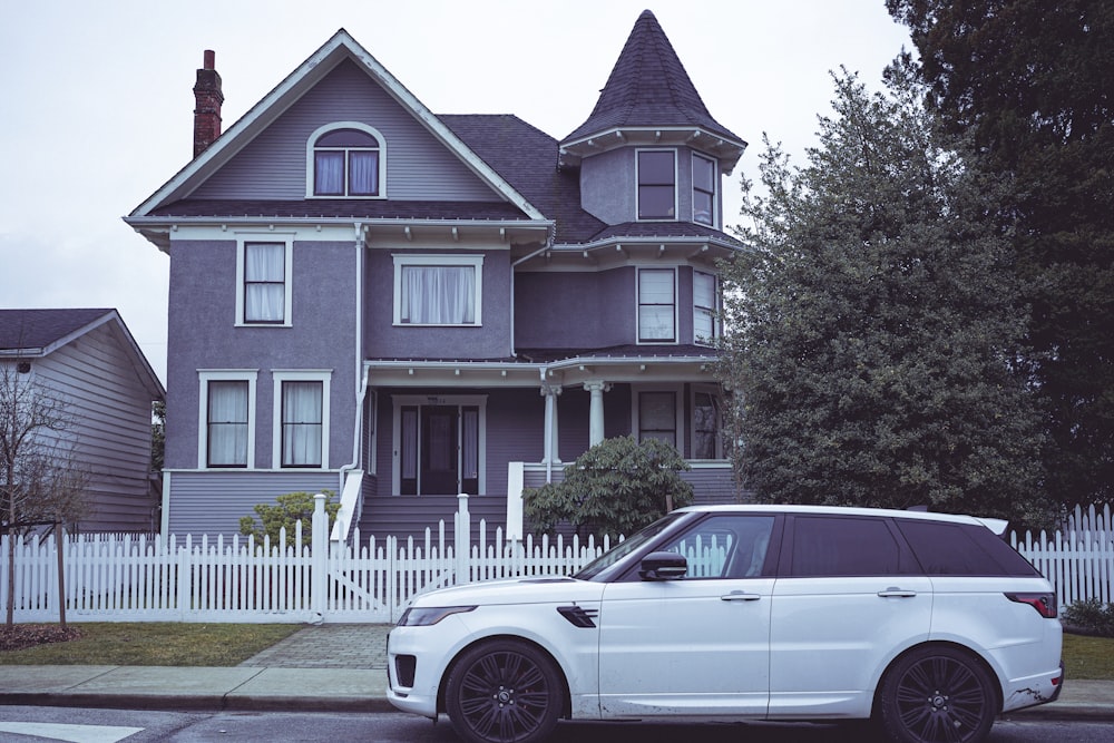 a white range rover parked in front of a house