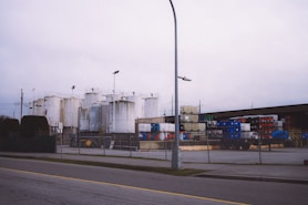 a street light next to a building with a lot of tanks behind it