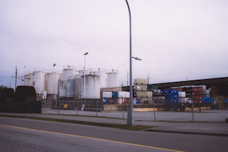 a street light next to a building with a lot of tanks behind it