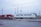 Two shipping containers, one red with 'CP' written on it and another white with 'Maritime-Ontario,' are situated on a gravel surface. Surrounding them are utility poles and wires, suggesting an industrial or logistics area. The sky appears overcast, adding to the subdued atmosphere.