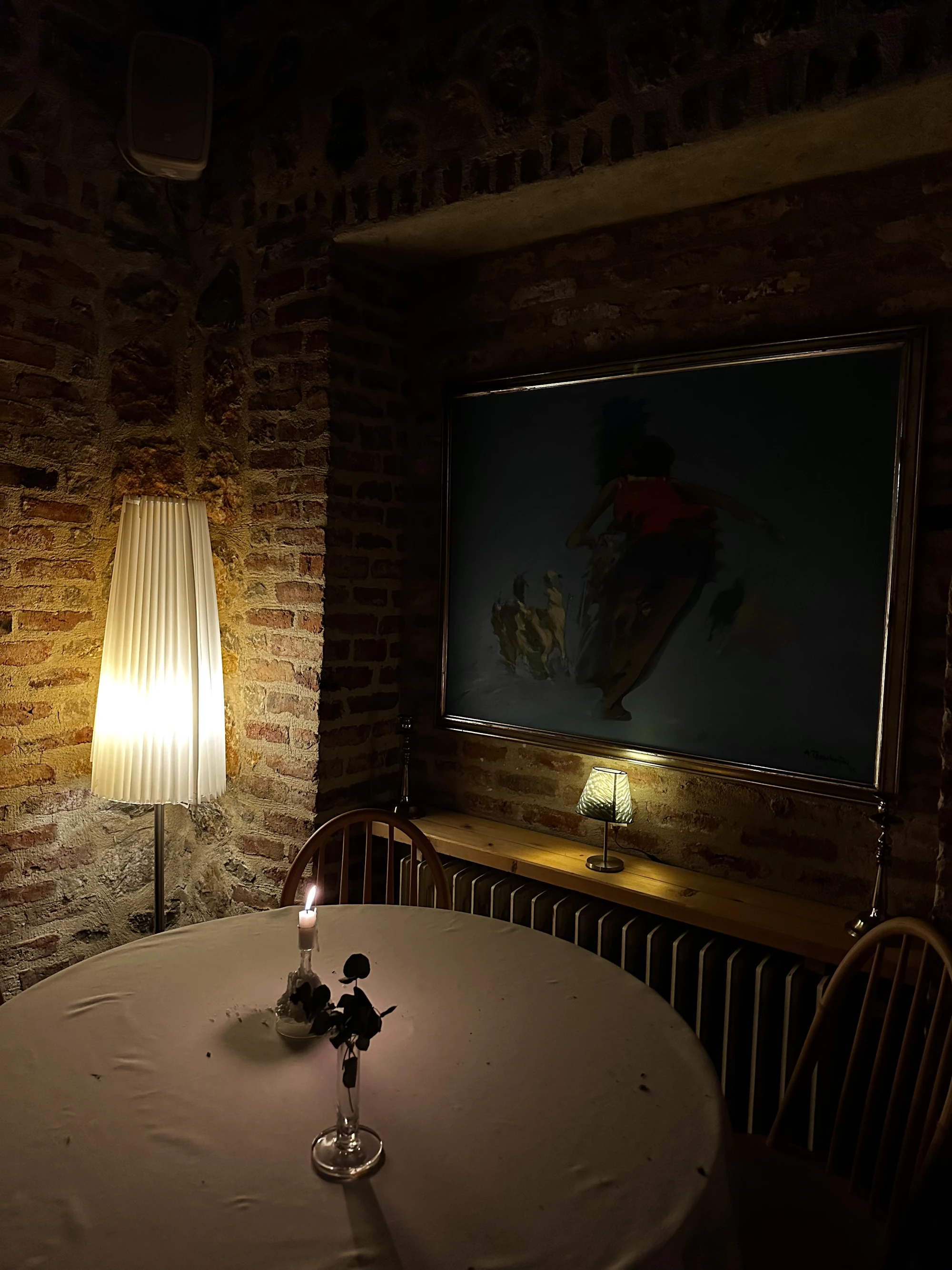 A single candle on a set table against the brick wall of the back room